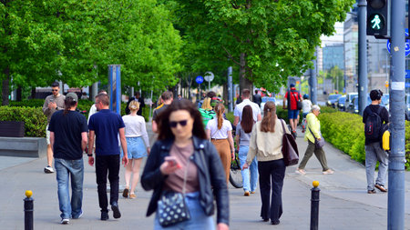 Warsaw, Poland. 20 May 2026. Street of a big city in summer time with residents, tourists and modern buildings. People of different ages crossing the road through.