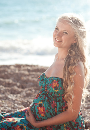 Laughing pregnant woman resting at beach outdoors. Motherhood. Maternity.の写真素材