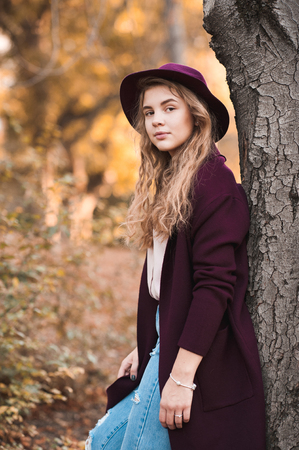 Beautiful teen girl 14-16 year old wearing stylish autumn clothes in park. Looking at camera. の写真素材