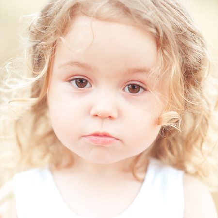 Close up portrait of sad baby girl. Looking at camera. Childhood.の写真素材
