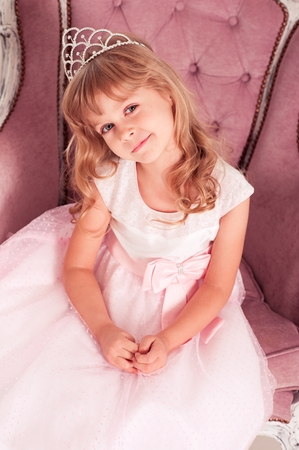 Closeup portrait of smiling kid girl 4-5 year old wearing princess dress and crown. Looking at camera. Celebrating birthday. の写真素材