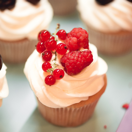 Tasty cupcake with fresh raspberry and currant, cream cheese on top closeup. Selective focus.の写真素材