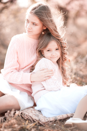 Two young girls sitting in field outdoors. Summer time.の写真素材