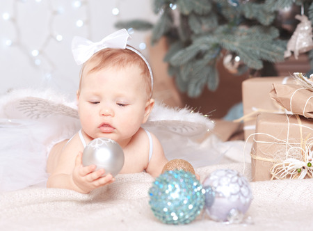 Cute baby girl playing with christmas decorations in roomの写真素材