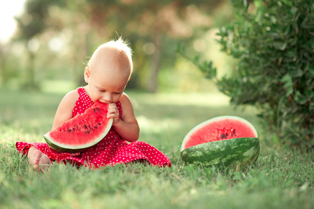 Cute baby girl eating watermelon outdoors. Healthy lifestyle. Organic food. Childhood.の写真素材