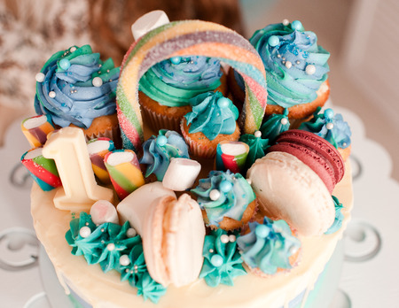 Birthday cake with sweets, cupcakes and macaroons closeup. Selective focus. の写真素材