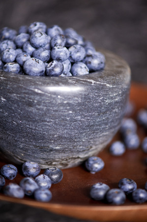 Marble bowl full with blueberries on wooden tray close up. Healthy eating. Selective focus. の写真素材