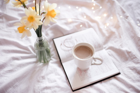 Good morning with fresh cup of coffee and reading in bed.