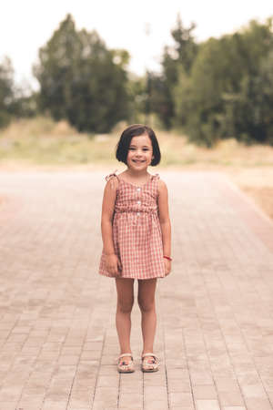 Funny cute child girl 3-4 year old wearing stylish dress posing in park closeup. Looking at camera. Summer season.の写真素材
