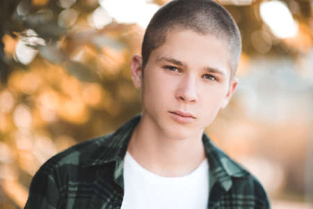 Handsome boy 18-20 year old posing over nature background closeup. Looking at camera. Teenagerhood.
