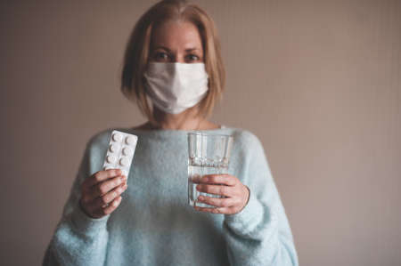 Adult woman wearing medical mask closeup. Looking at camera. Home quarantine. European.