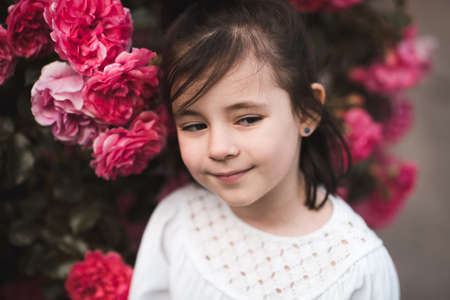 Happy child girl 3-4 year old holding pet dog over nature background closeup. Looking at camera. Selective focus on puppy. Summer season.の写真素材