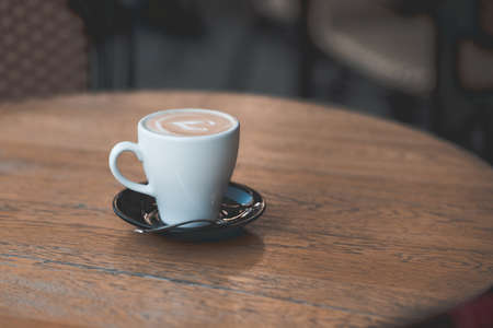 Cup of cappuccino staying on wooden table in cafe close up. Good morning. Coffee break.