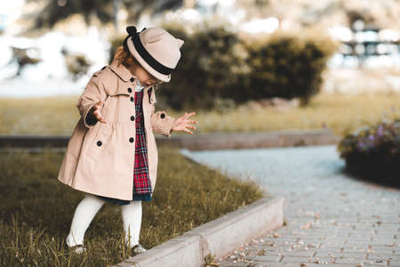 Cute baby girl 1-2 year old holding teddy bear outdoors. Looking at camera. Childhood.