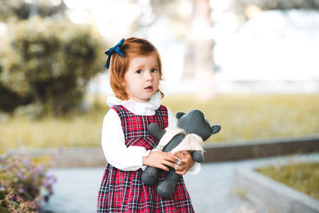 Cute baby girl 1-2 year old holding teddy bear outdoors. Looking at camera. Childhood.