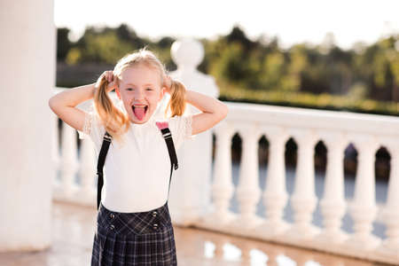 Laughing kid girl 5-6 year old wearing checkered skirt outdoors. Back to school. Pre schooler.の写真素材