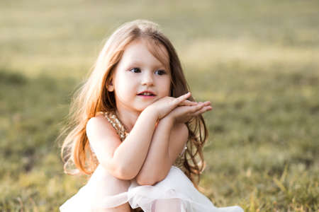 Funny baby girl 4-5 year old eating watermelon sitting on green grass outdoors having picnic close up. Harvesting time.の写真素材