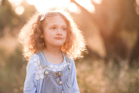 Pretty child girl 3-4 year old posing over sunny light background closeup. Summer time.の写真素材