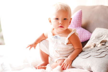 Cute baby girl sitting in bed. Good morning. Childhood.の写真素材