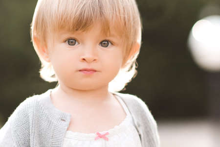 Cute baby girl 1-2 year old closeup over nature background outdoors in sun light. Looking at camera. Childhood. Summer time.の写真素材