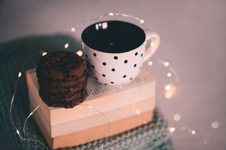 Tasty chocolate american cookies with cup of hot tea over Christmas light at back. Winter season holidays. Good morning. Night time.の写真素材