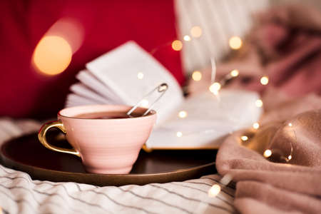 Morning tea with open book at bakground with lights.