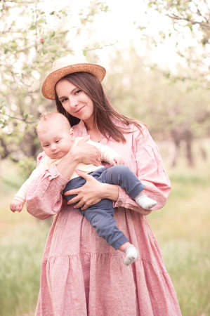 Mother holding baby posing outdoor over green nature background.の写真素材