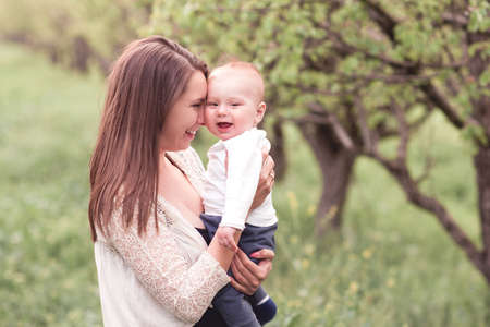 Mother holding baby posing outdoor over green nature background.の写真素材