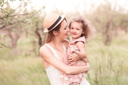Smiling woman holding kid girl 2-3 year old outdoors. Happiness. Motherhood.