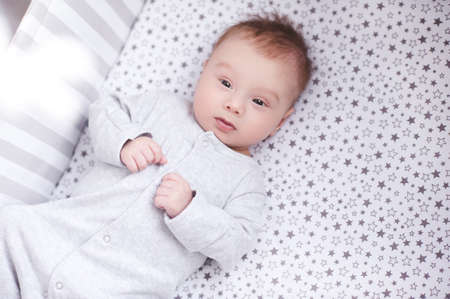 Cute baby lying in bed closeup. Looking at camera. Childhood. Good morning.