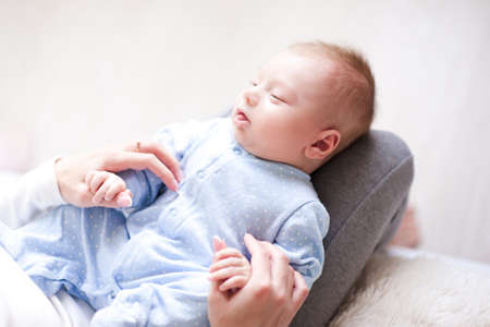 Mother feeding baby boy 2-3 months old with milk in bottle closeup. Motherhood. Maternity.