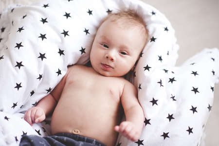 Cute baby lying in bed closeup. Looking at camera. Childhood. Good morning.