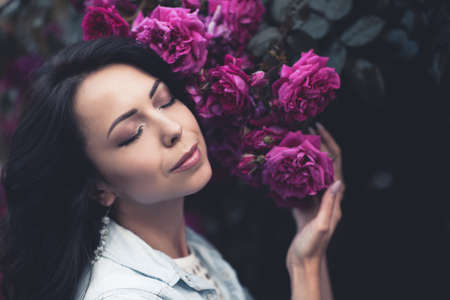 Stylish young girl 24-25 year old posing with roses at city street outdoors. 20s. Fashionable.の写真素材
