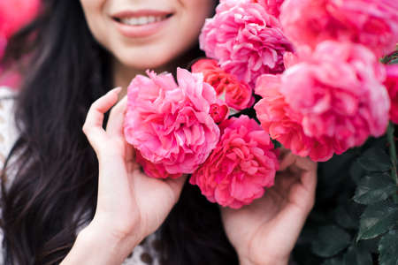 Stylish young girl 24-25 year old posing with roses at city street outdoors. 20s. Fashionable.の写真素材