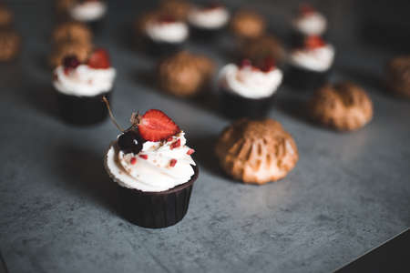 Cupcake with cream cheese top decorated with strawberry on kitchen table closeup. Good morning....