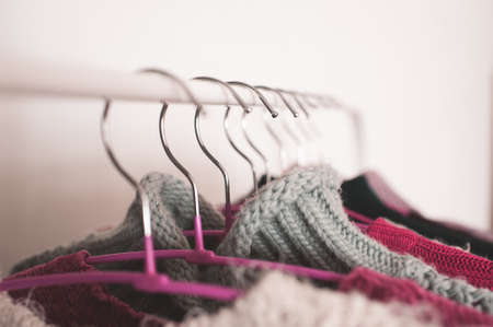Clothes hangers with knitted winter clothes closeup. Selective focus.