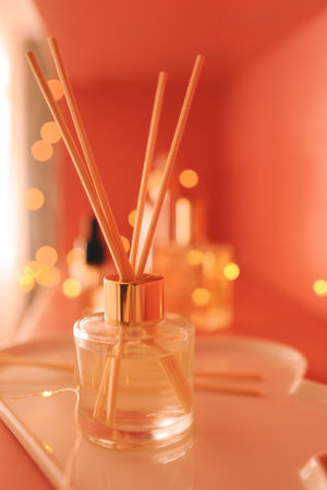Aroma liquid scented fragrance with wooden sticks with glowing lights and skin care products close up in room. Wellness.の写真素材