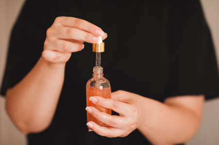 Woman holding moisturizing facial serum in glass bottle close up. Skin health care. Healthy lifestyle.の写真素材
