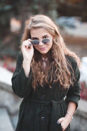 Stylish blonde teenage girl 15-16 year old wearing spring jacket wearing sun glasses posing outdoors close up. Looking at camera. Teenagerhood.の写真素材