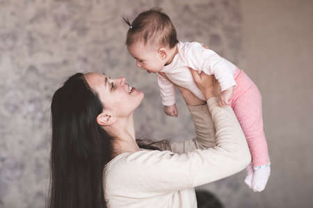 Mother holding baby girl at home. Newborn child on woman hands indoors. Motherhood. Maternity.の写真素材