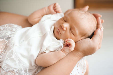 Sleeping cute little baby under 1 year old lying on mother hands in room at home close up....