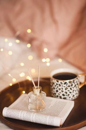 Cup of black fresh coffee with liquid aroma perfume in glass bottle with wood sticks and open paper...