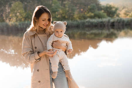 Smiling young mother playing with baby boy 1 year old wear casual clothes posing over nature...