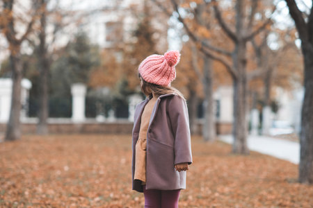 Happy smiling child 4-5 year old wear jacket and hat in park with fallen leaves over nature background. autumn season. Childhood.の写真素材