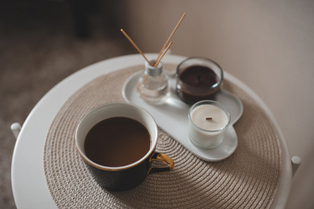 Cup of fresh coffee with scented candles and liquid home fragrance in glass bottle with bamboo...