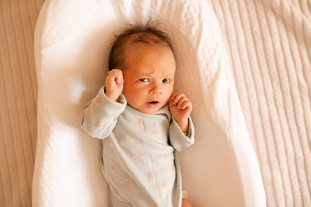 Little frightened infant baby girl wake up lying in crib close up top view. Childhood.の写真素材