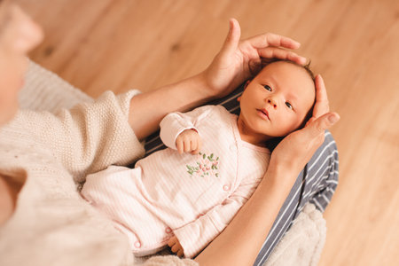 Mother holding cute infant baby girl on hands wear pajamas in room at home top view. motherhood.の写真素材