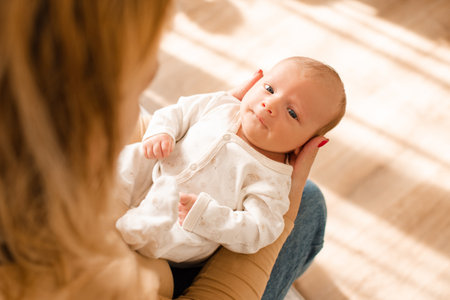 Mother holding little infant baby 1-2 months old on hands in home room closeup top view. motherhood.の写真素材