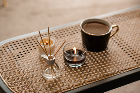 Cup of tea with liquid home perfume in glass bottle and scented candle on rattan table closeup. aromatherapy.の写真素材