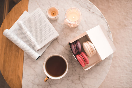 Cup of tea with open book and snacks on marble table close up. Top view. Good morning.の写真素材